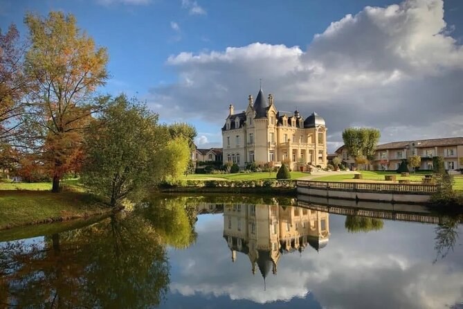 A turreted château mirrored in its lake, trees turning in autumn