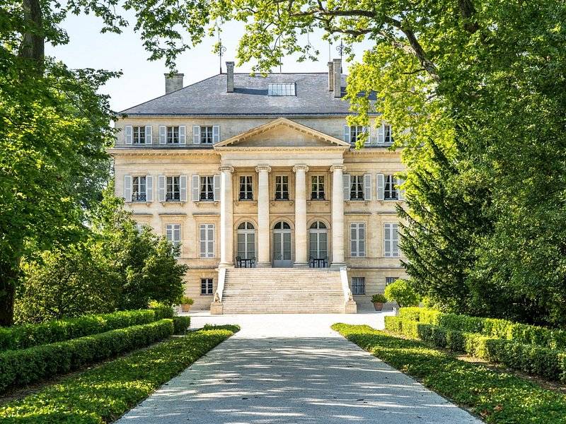 A château's columned portico at the end of a hedged alley