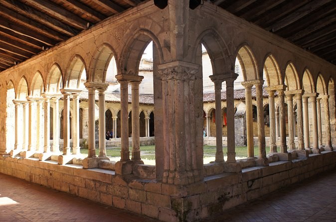 A cloister's arcade of paired columns under a timber roof