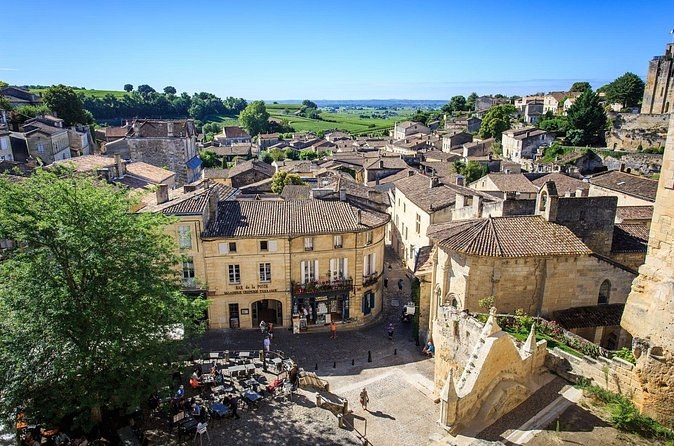 Saint-Émilion's stone roofs and a square of café tables seen from above