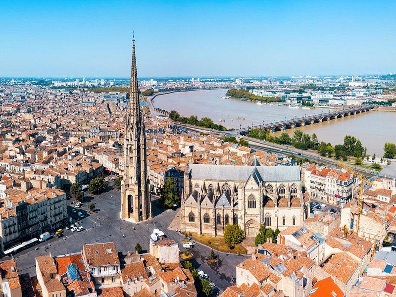 The Saint-Michel spire and basilica above Bordeaux's roofs, the Garonne and the Pont de Pierre beyond